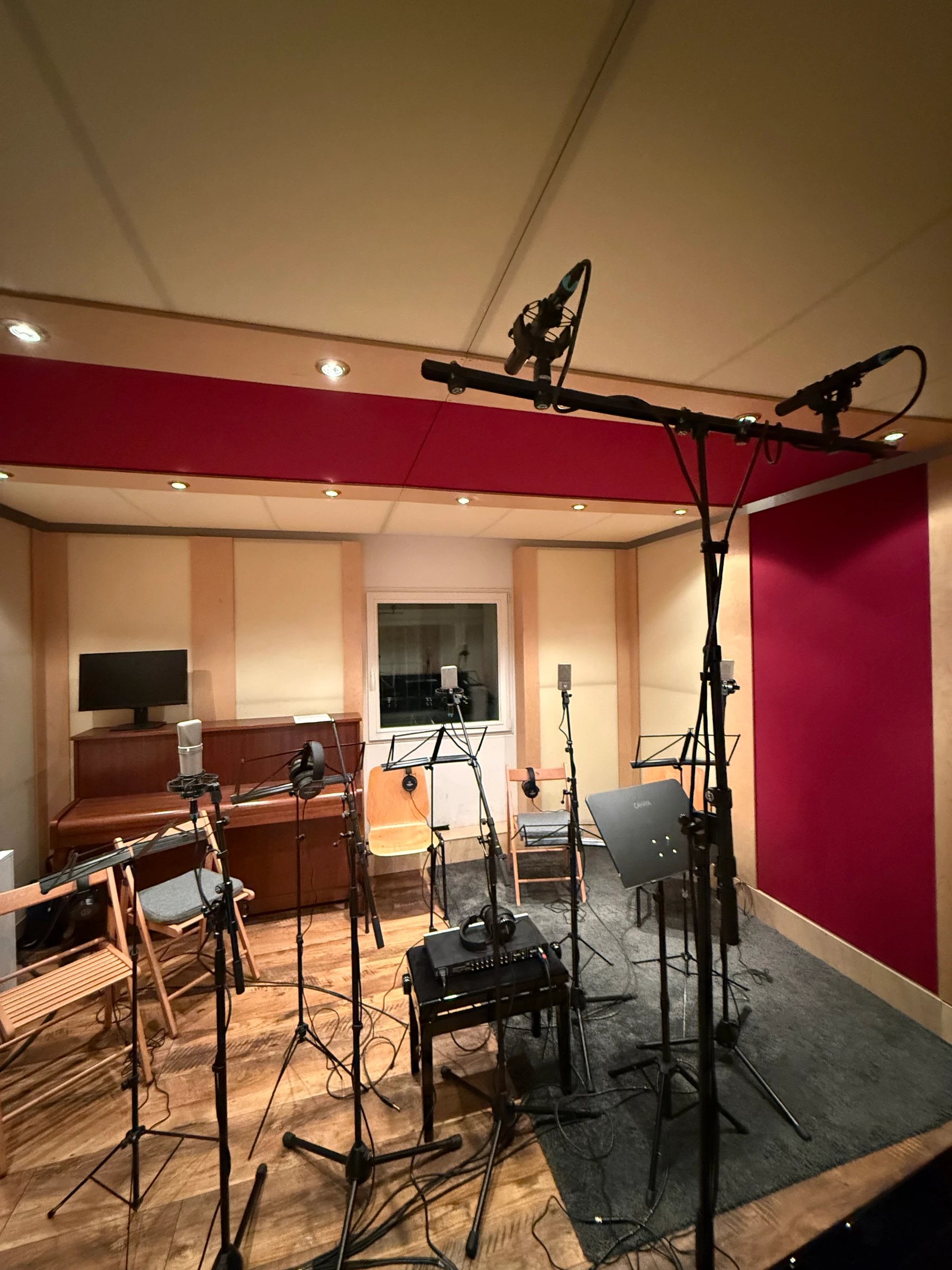 Live room wide angle — mic stands, cables, burgundy wall and acoustic treatment