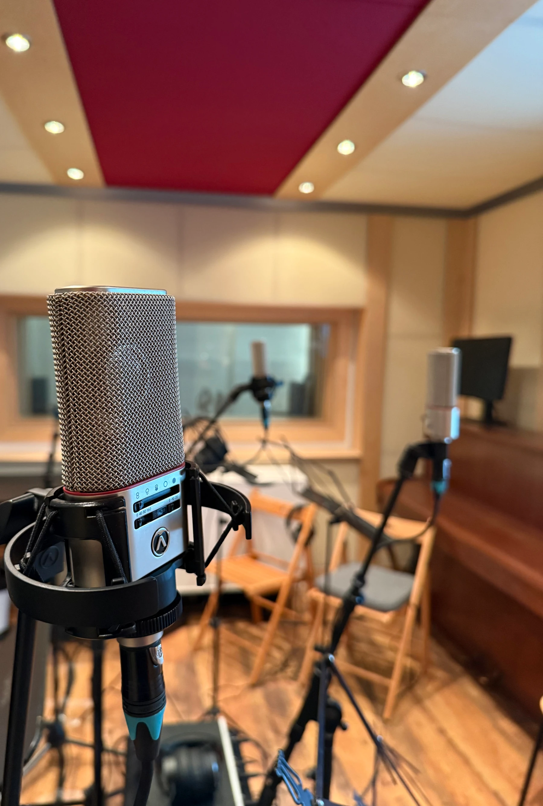 Austrian Audio microphone in the live room with piano and window to control room